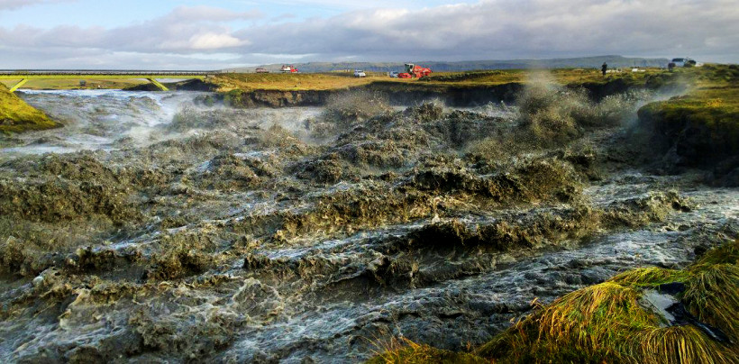 Skaftá er í gríðarleg­um ham, svört af aur og æðir yfir grasi gróna bakka sína.