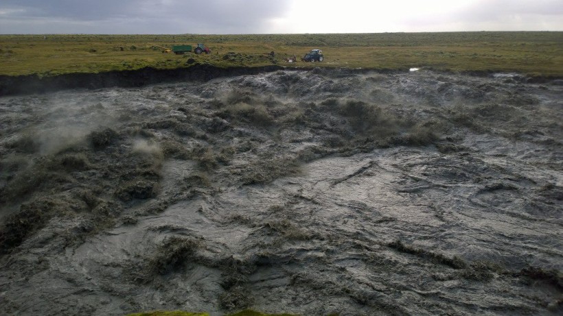 Skaftá er í gríðarleg­um ham, svört af aur og æðir yfir grasi gróna bakka sína.