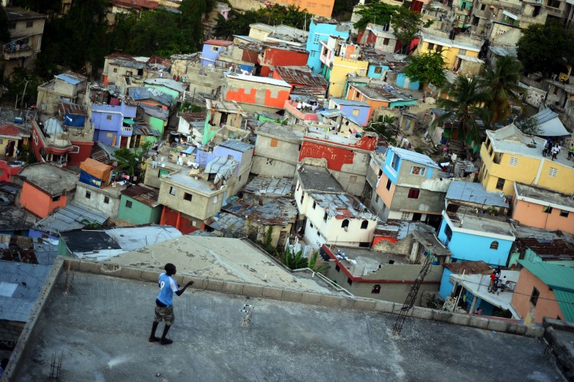 Barn leikur sér með flugdreka á þaki húss í Port au Prince á Haítí.