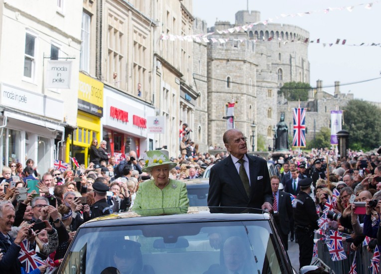 Elísabet Bretlandsdrottning og Filippus drottningarmaður veifa til þegnanna á leið til Windsor-kastala í dag.